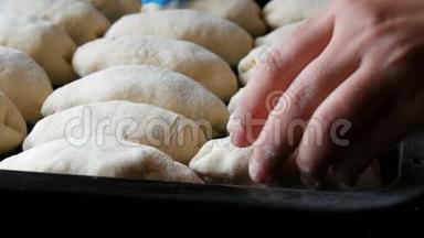 女人的手面包师把自制的烘焙面团以细长的圆球的形式连续放置在黑色烘焙片上
